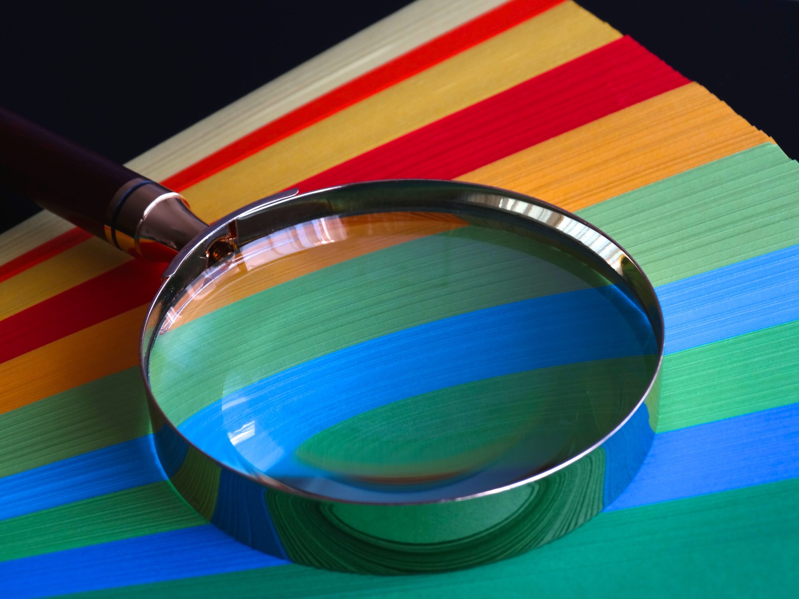 Magnifying glass over coloured paper - Rachel Writes proofreading service